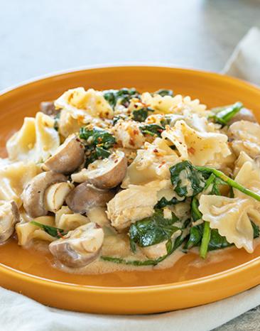Pasta mit Hühnchen Spinat und Champignons auf einem tiefen Teller