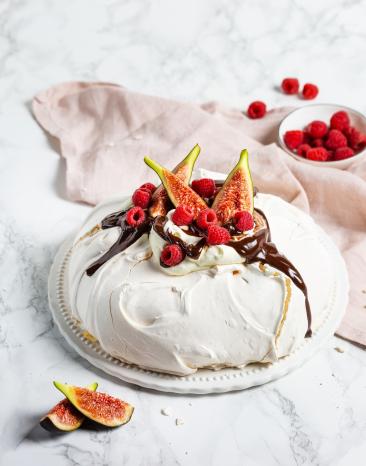 Pavlova auf Teller, Schale mit Beeren und rosa Tuch