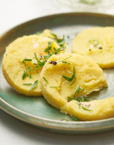 Polenta als Taler mit Petersilie auf einem Teller.