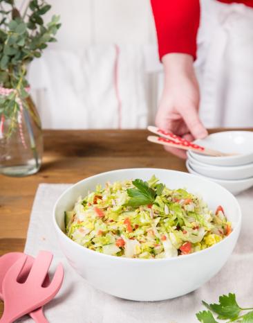Eisbergsalat mit Gemüse in großer weißer Schüssel.
