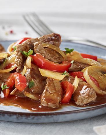 Rindergeschnetzeltes mit Schwammerl und Paprika auf einem Teller.