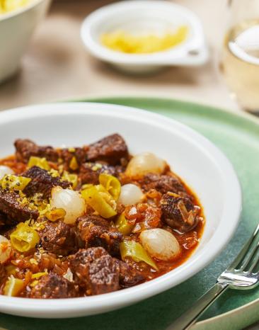 Rindergulasch mit Perlzwiebeln aus dem Cookit auf einem Teller angerichtet.