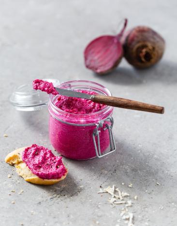 Rote-Bete-Aufstrich im Glas mit Messer und Stück Baguette