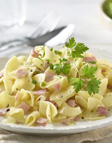 Schinkenfleckerl auf einem Teller mit Petersilie angerichtet.