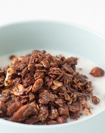 Schokoladen-Granola mit Milch in Schüssel.