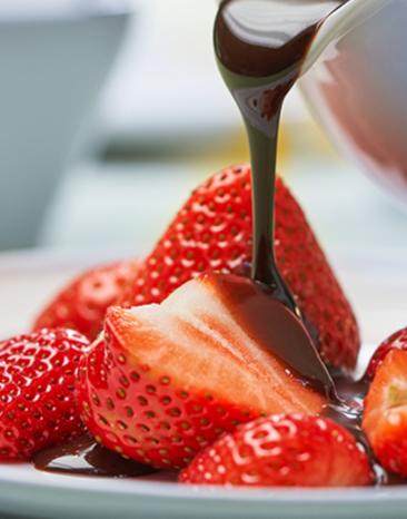 Schokoladensauce wird über Erdbeeren gegossen.