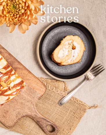 Schweizer Bananenrolle auf Brett mit Kuchentellern und Besteck