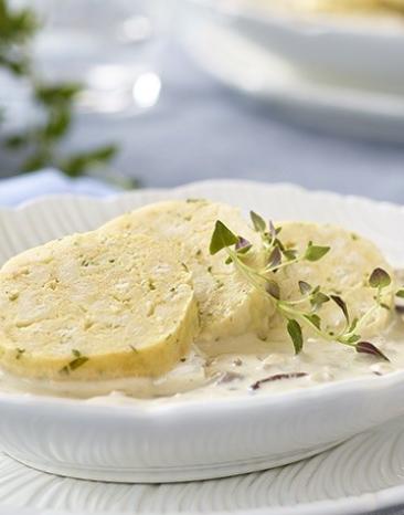 Serviettenknödel in Schwammerlsauce auf einem Teller angerichtet.