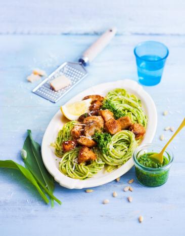 Spaghettini mit Bärlauchpesto und gebratenem Hähnchen auf einem Servierteller.
