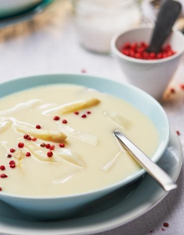 Spargelcremesuppe mit rotem Pfeffer garniert in einem Teller.