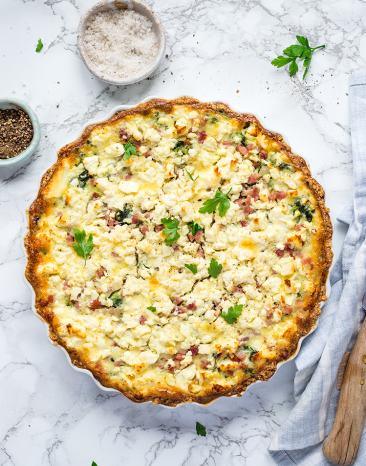 Spinat-Speck-Quiche auf einem Tisch.