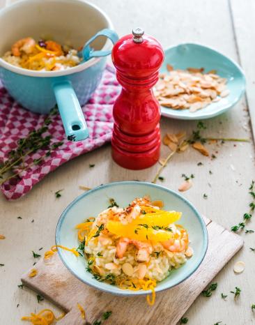 Thymian-Orangen-Risotto mit Garnelen und Mandeln auf einem tiefen Teller angerichtet. 