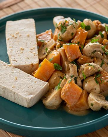 Tofu gedämpft mit Kürbis und Champignons auf einem Teller.