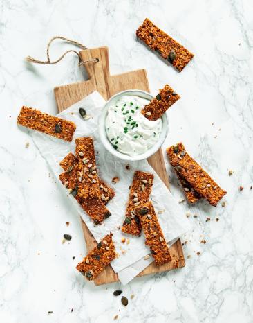 Mehrere Tomaten-Karotten-Cracker mit Pesto auf Schiefertafel.