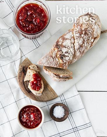 Tomatenmarmelade auf Brotscheiben und in einem Töpfchen auf einem Tisch.