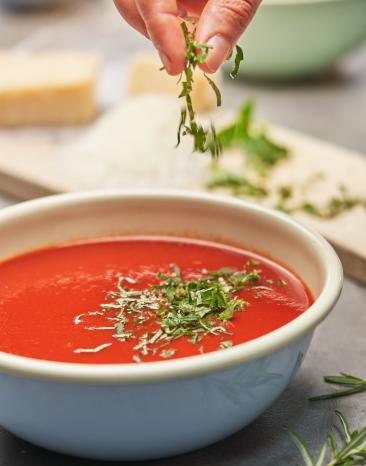 Tomatensugo wird mit Kräutern garniert in einer Schale.