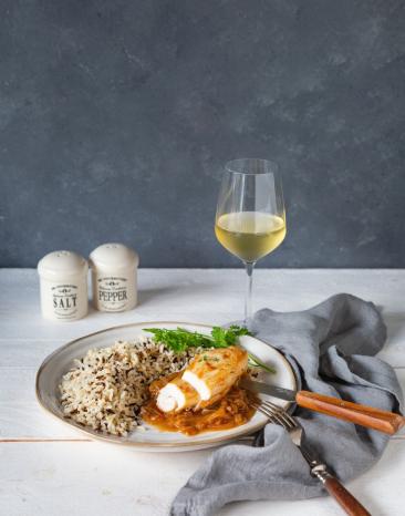 Hähnchen und Reis auf Teller mit Besteck, Weinglas und Tuch