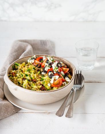 Zucchini-Bulgur mit Feta und Tomaten in Schüssel mit Besteck