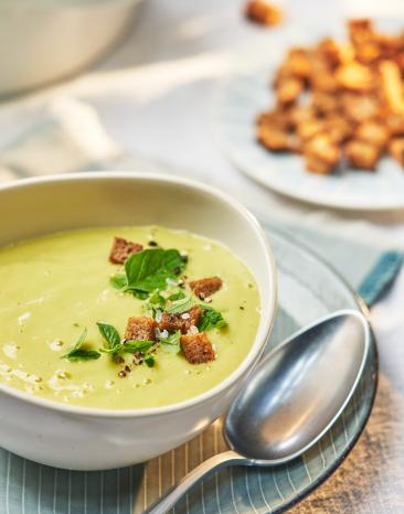 Zucchini-Kartoffel-Suppe in einem Teller mit Brotcroûtons garniert.