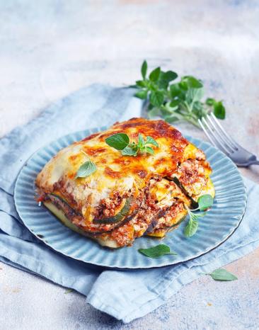 Ein Stück Zucchinilasagne aus dem Cookit auf blauem Teller.