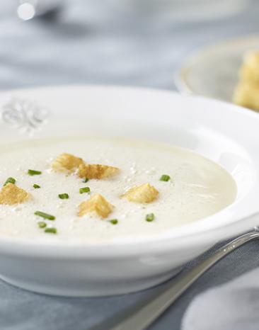 Zwiebelcremesuppe mit Weißbrotcroûtons in einem Teller angerichtet.
