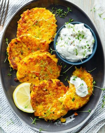 Gemüse-Kartoffel-Puffer mit Kräuterdip auf einem Teller.