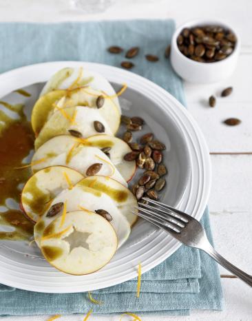 Kohlrabi-Apfel-Carpaccio mit Kürbiskernen auf einem Teller.