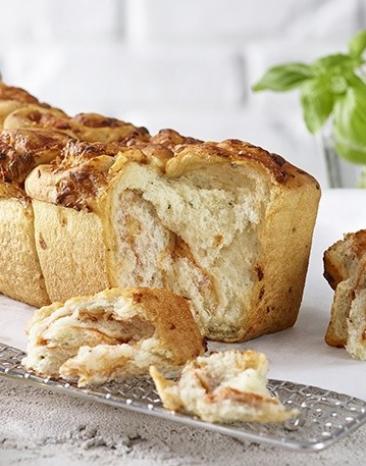 Pizza-Zupfbrot auf einem Gitter mit Backpapier.