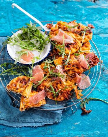 Schnelle Pizzawaffeln auf einem Gitter mit Schinken und Rucola.