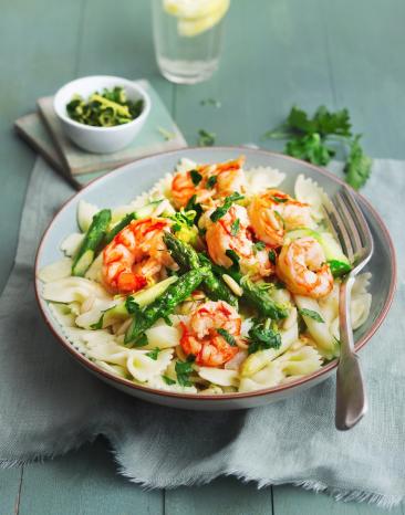 Farfalle mit gebratenem Spargel und Garnelen in einem tiefen Teller.