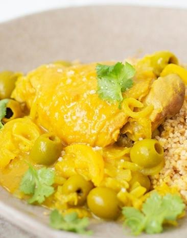 Hähnchen-Tajine mit eingelegten Zitronen und grünen Oliven in einem tiefen Teller.