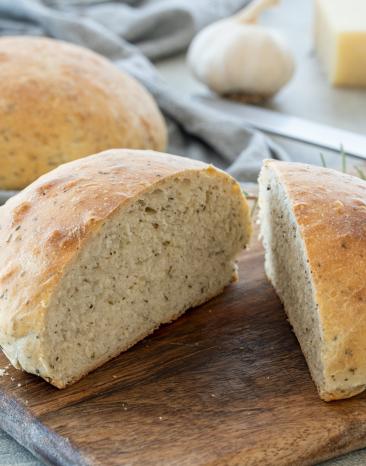 Rustikales Parmesan-Knoblauch-Brot angeschnitten auf einem Holzbrett.