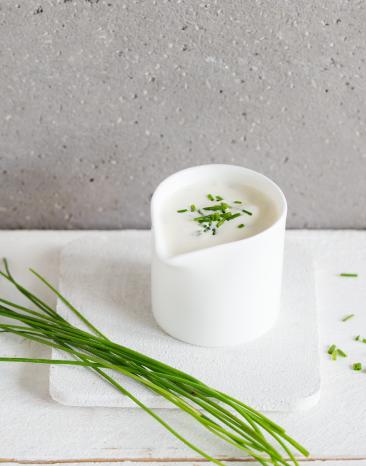 Sour Cream mit Schnittlauch in einem Saucenkännchen.
