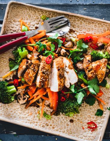 Teriyaki Chicken mit gedämpftem Gemüse auf einem Teller.