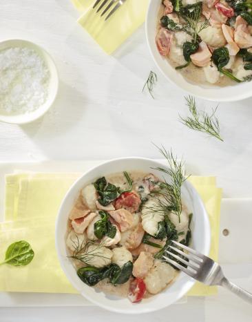 Gnocchi mit Lachs-Spinat-Sauce in zwei tiefen Tellern.