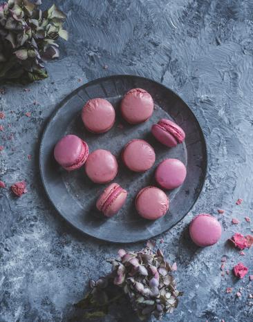 Rosa Macarons auf einem grauen Teller.