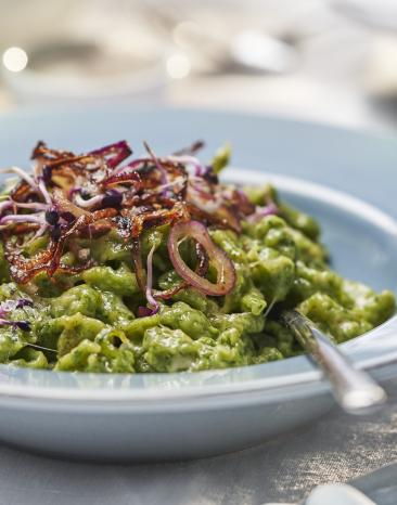 Grüne Käsespätzle mit Röstzwiebeln auf einem Teller.