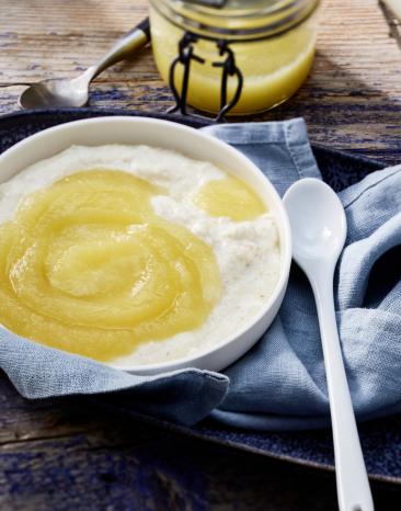 Heller Brei mit Apfelmus im Schälchen mit kleinem Löffel.