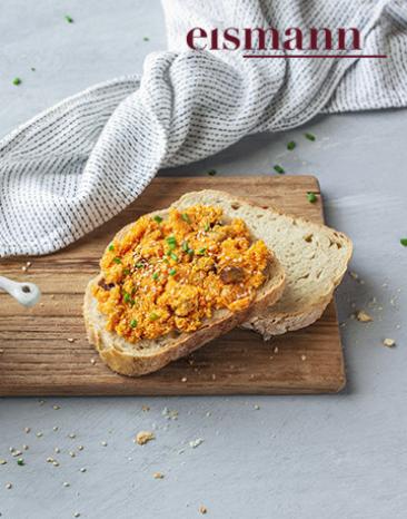 Orange farbender Aufstrich in einem Schälchen und einem Stück Brot.