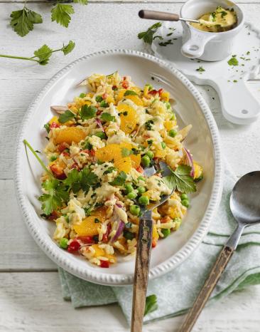 Reissalat mit Currysauce und Mandarinen in einer Servierschale.