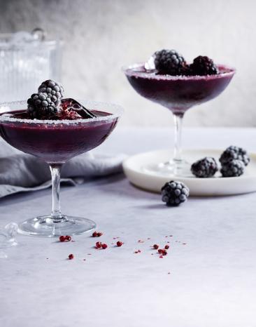 Dunkel roter Drink in einem Cockteilglas mit Beeren.