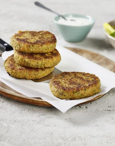 Bralinge auf einem Teller. Im Hintergrund ein Dip und Salat in Schälchen.
