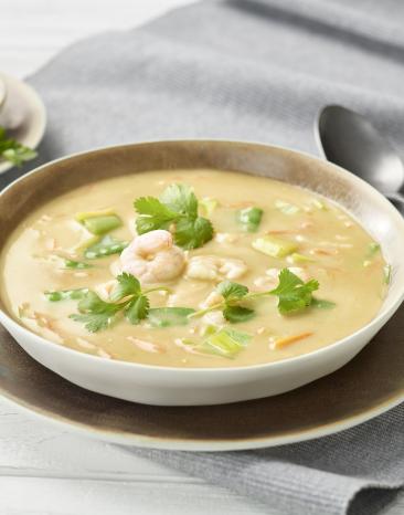 Suppe mit Garnelen und Petersilie in einem tiefen Teller.