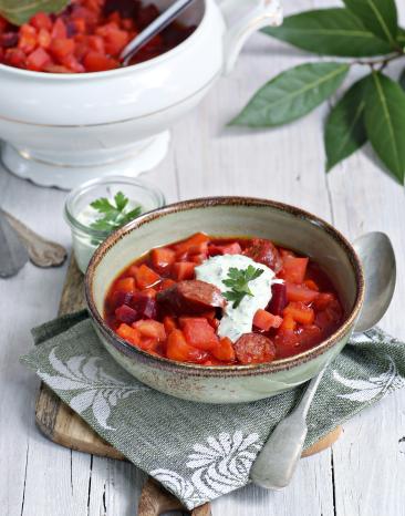 Eintopf mit roter Farbe und einem klecks Creme oben drauf.