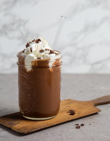 Dunkle Trinkschokolade in einem Glas mit Sahne.