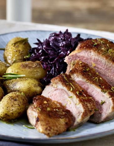 Entenbrust mit Rosmarin-Kartoffeln und Rotkohl auf einem Teller.