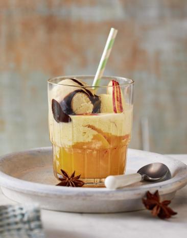 Orangener Punsch mir Mandarinen in einem Glas mit Strohhalm.