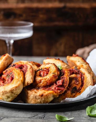 Pizzabrötchen auf Teller mit Glas im Hintergrund.