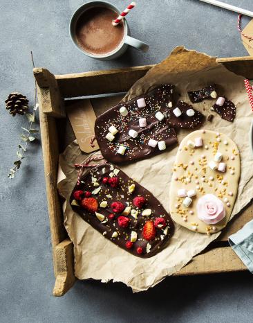 Bruchschokolade mit bunten Topping auf einem Holztablett.
