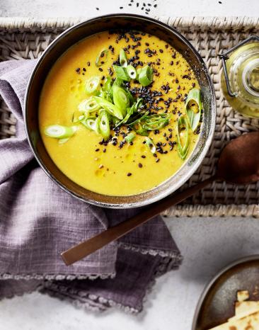 Süßkartoffelsuppe mit Frühlingszwiebeln und Pfeffer in einer Schüssel.